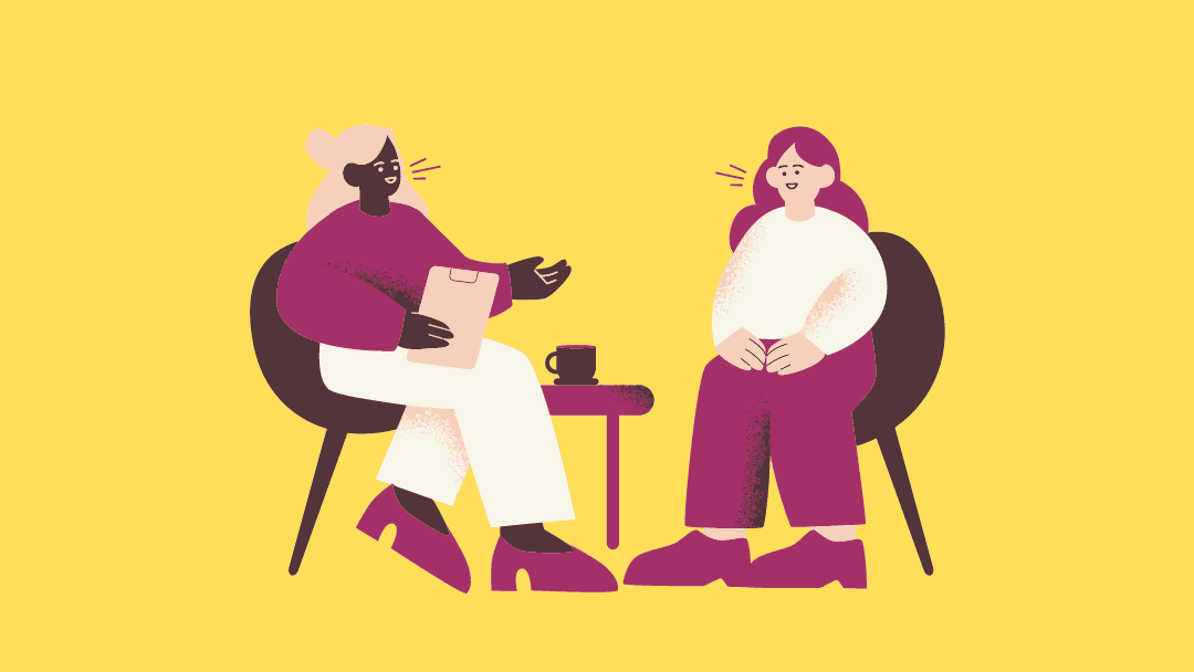 A mentor and mentee (two women) seated and having a conversation with each other. The Mentor listens to her mentee with her accomplishment and challenges.